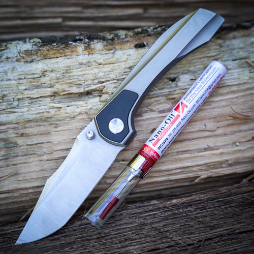 Brian Brown Raptor folding knife and a tube of Nano-Oil on a wooden surface