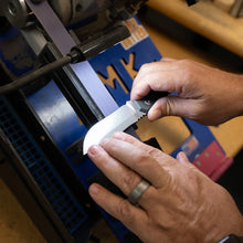 Load image into Gallery viewer, Person sharpening a knife using a belt sanding machine 